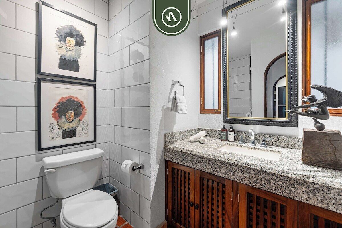 A bathroom with a toilet, sink, and framed artwork on the wall.