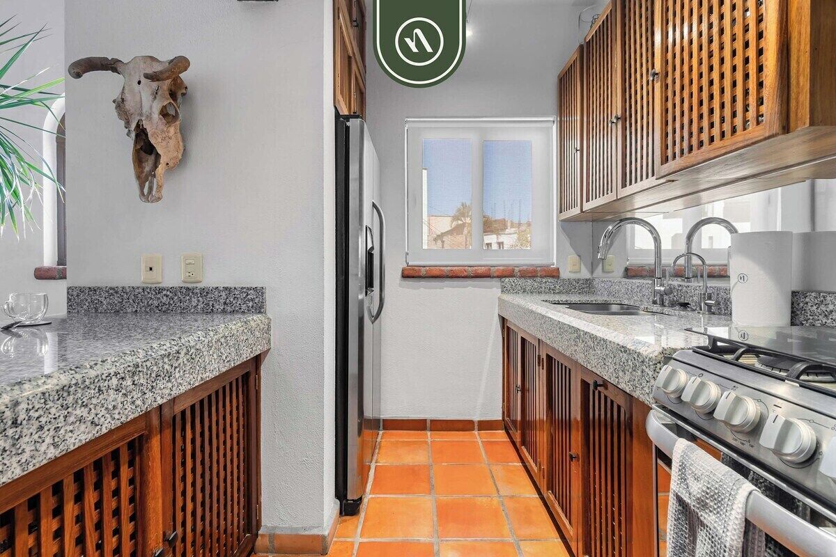 Une cuisine dotée de plans de travail en granit, d’une cuisinière, d’un réfrigérateur, de meubles en bois et d’une décoration représentant une tête de taureau.