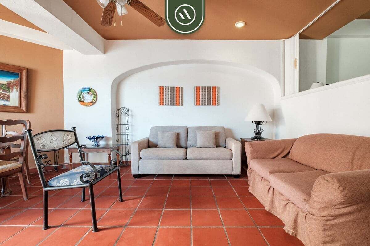 Un salon comprenant un canapé, un fauteuil, une lampe et un mur décoratif.