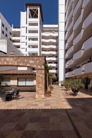 Un patio con un arco de piedra, plantas en macetas y mobiliario exterior.