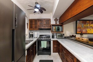 Une cuisine équipée d’un réfrigérateur, d’une cuisinière, d’un four à micro-ondes et de meubles de rangement en bois.