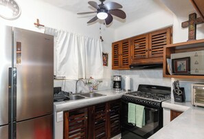 A kitchen with a refrigerator, stove, sink, and wooden cabinets.