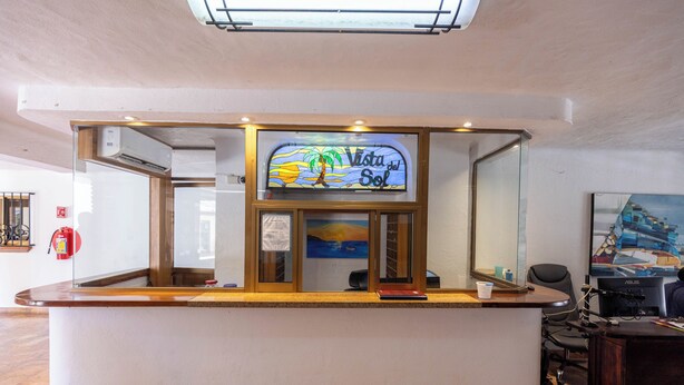 A reception desk with a sign reading 'Vista del Sol,' a fire extinguisher, and a painting on the wall. - Ocean View 2Br Condo-balcony-beach-pool - 902 (Puerto Vallarta)