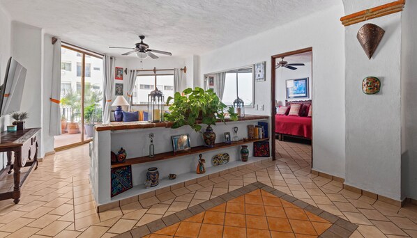 Amplia sala de estar con una isla central, ventilador de techo y vistas al exterior.