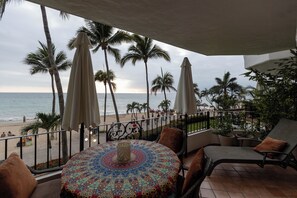Ein Balkon mit Blick auf den Strand, Palmen und einer gemusterten Tischdecke.