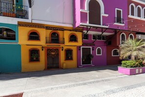 A colorful building with a yellow facade, multiple windows, and a balcony.