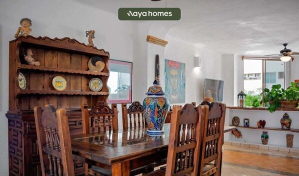 Un comedor con muebles de madera, un jarrón decorativo grande y una estantería con varios objetos.