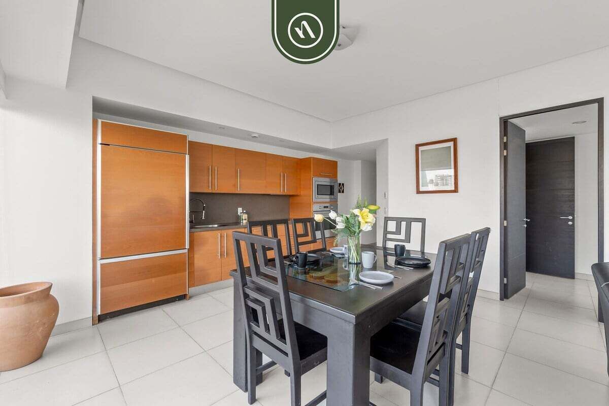 A modern kitchen with wooden cabinets, a dining table with chairs, and a small dining area.