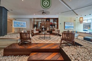 A modern interior with a central seating area, a bookshelf, and a view of the outdoors.