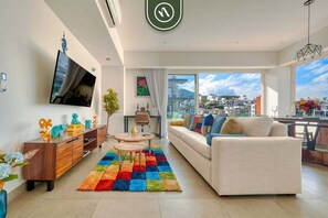 A modern living room with a sofa, TV, and a colorful rug.