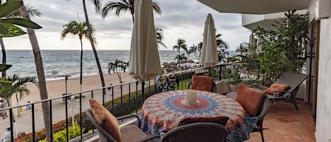Un balcón con sillones de mimbre, un mantel estampado y vista al océano.