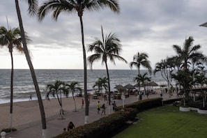 A beachside promenade with palm trees, a beach, and a restaurant area.