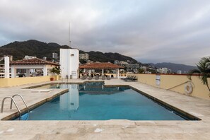 Une piscine offrant une vue sur la ville et les collines en arrière-plan.