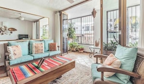 A spacious living room with a sofa set, a coffee table, and a chair. There is a large window with a view of the street. - Beach Front Building 2Br Condo-balcony-beach-pool (Puerto Vallarta)