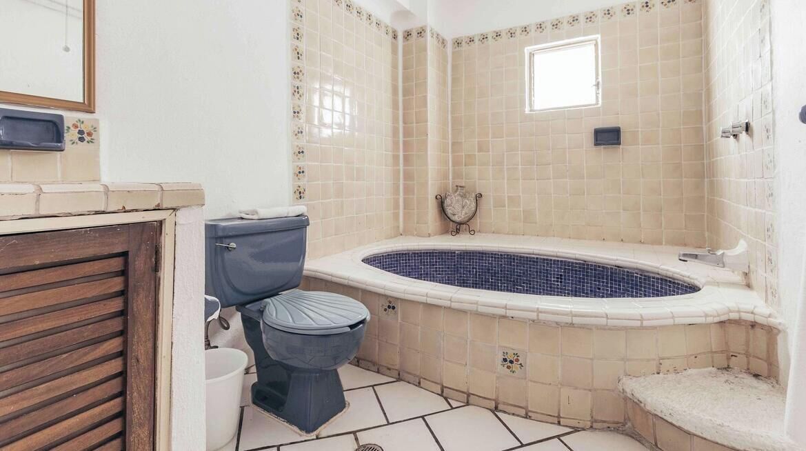 Ein Badezimmer mit Toilette, Waschbecken, Badewanne und gefliesten Wänden.