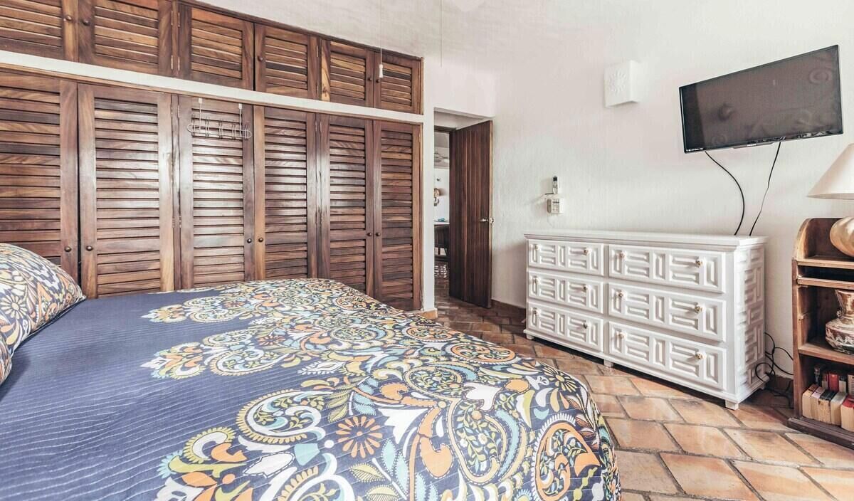 Une chambre à coucher avec un lit, une armoire, une télévision et une commode.