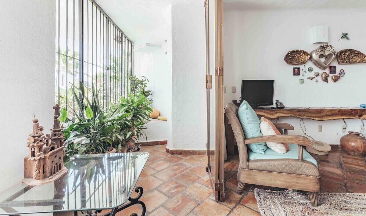 A room with a wooden chair, a glass table, a TV, and decorative items on the wall.