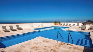 Ein Swimmingpool mit Liegestühlen und Blick auf den Ozean.