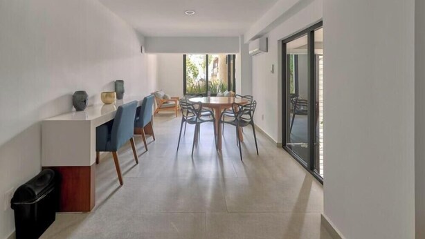A modern interior with a dining area, a kitchen counter, and a large sliding glass door leading to an outdoor space.