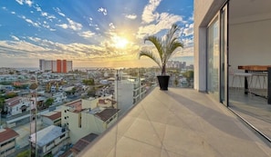 Un balcon avec vue sur la ville, une plante en pot et une table avec des chaises.