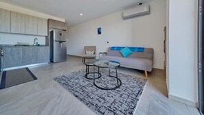A modern apartment with a kitchen, a living area with a sofa and a coffee table, and a small dining table.