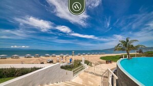 Un resort con piscina, playa y una escalera que lleva a una terraza.