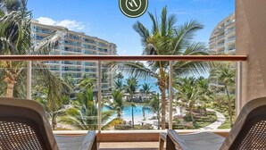 Un balcón con vistas a una piscina y palmeras, que da al edificio de un hotel.
