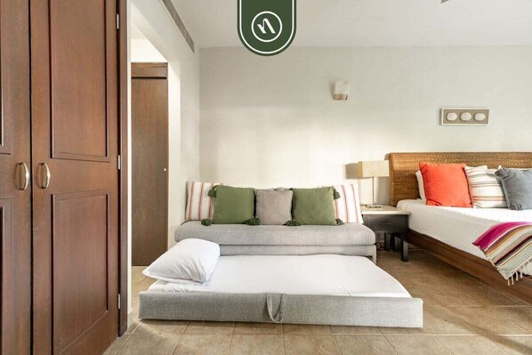 Une chambre comprenant un canapé-lit, un lit simple et une armoire en bois.