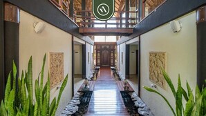 A corridor with a central walkway flanked by stone railings and green plants, leading to a wooden door at the end. - 3BR Condo in the Krystal Grand Hotel - Beach (Nuevo Nayarit)