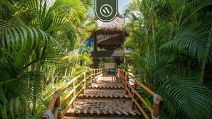 A wooden staircase with a thatched roof structure at the end, surrounded by lush greenery. - 3BR Condo in the Krystal Grand Hotel - Beach (Nuevo Nayarit)