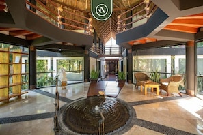 A spacious lobby with a central water feature, wooden furniture, and large windows. - 3BR Condo in the Krystal Grand Hotel - Beach (Nuevo Nayarit)