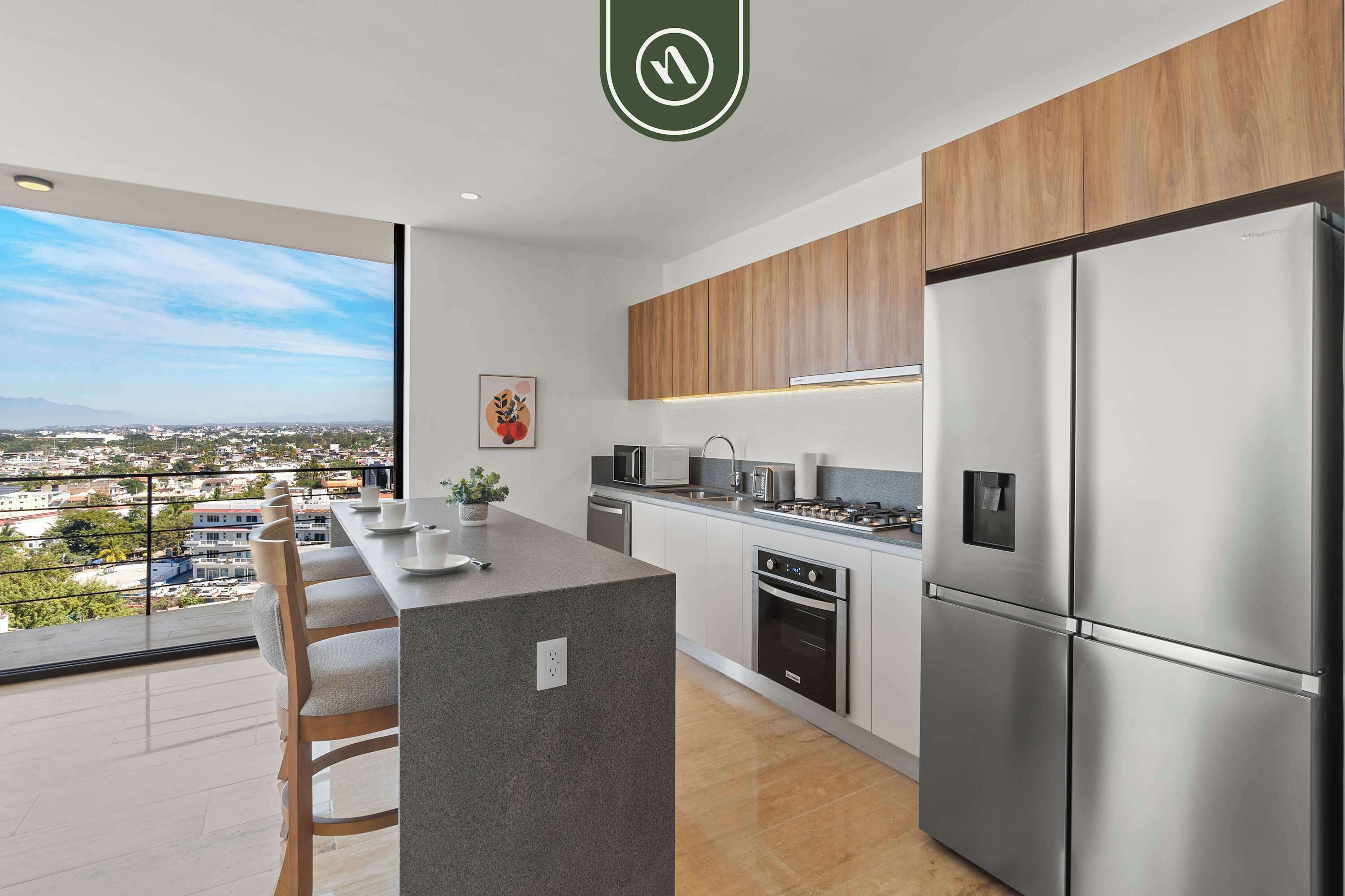 Cozinha moderna com uma ilha grande, eletrodomésticos de aço inoxidável e vista para a cidade.