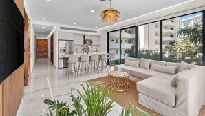 Un salon moderne avec un canapé, une table basse et un coin cuisine à l’arrière-plan.