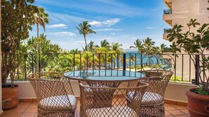 A round table with wicker chairs on a balcony with a view of the ocean and palm trees. - Ocean View 2Br Condo-balcony-beach-pool - 304 (Puerto Vallarta)