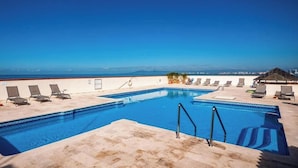Una piscina con sillones de descanso y vista al mar.