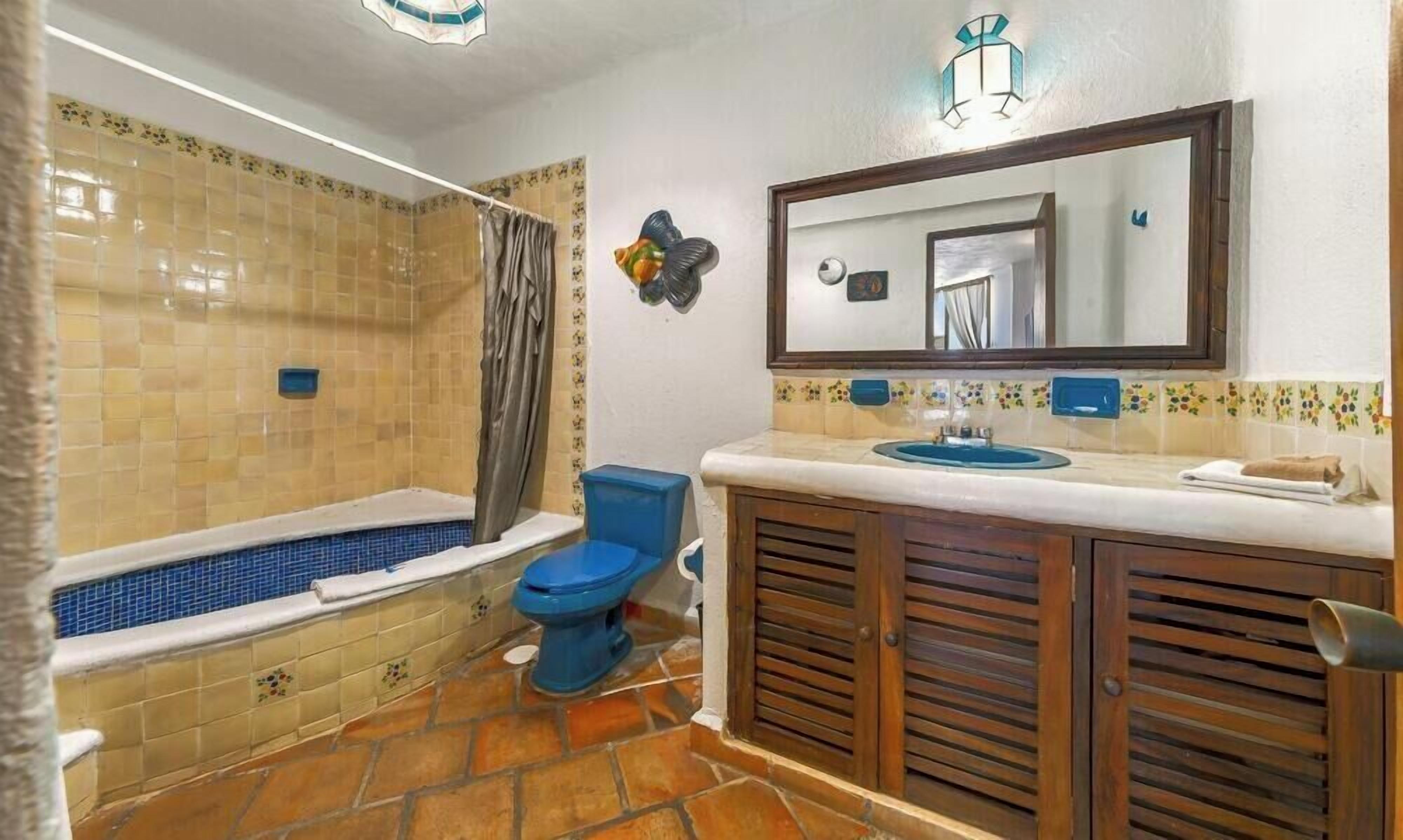 Een badkamer met een bad, toilet, wastafel en spiegel.