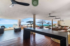 A spacious outdoor area with a wooden deck, lounge seating, and ceiling fans. - Centric 1 BR Condo With Gym Amazing Rooftop Pool (Puerto Vallarta)