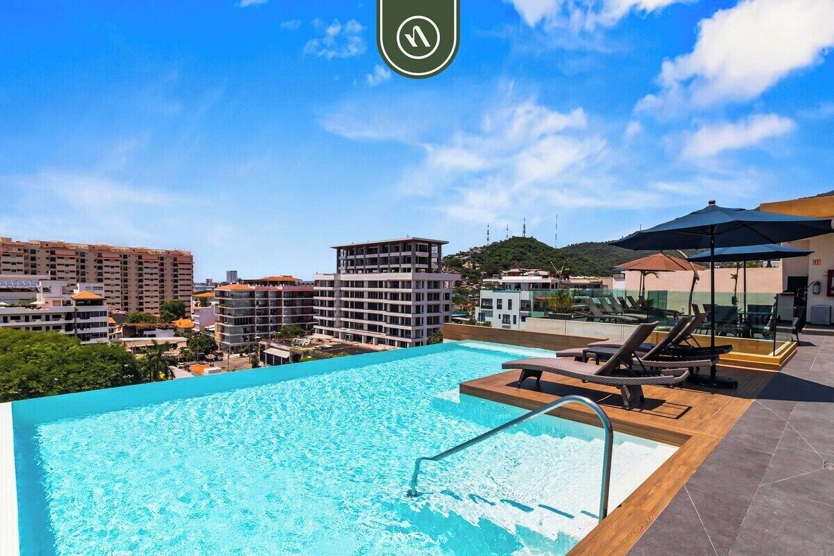 Ein Pool auf dem Dach mit Blick auf umliegende Gebäude und einen klaren Himmel.