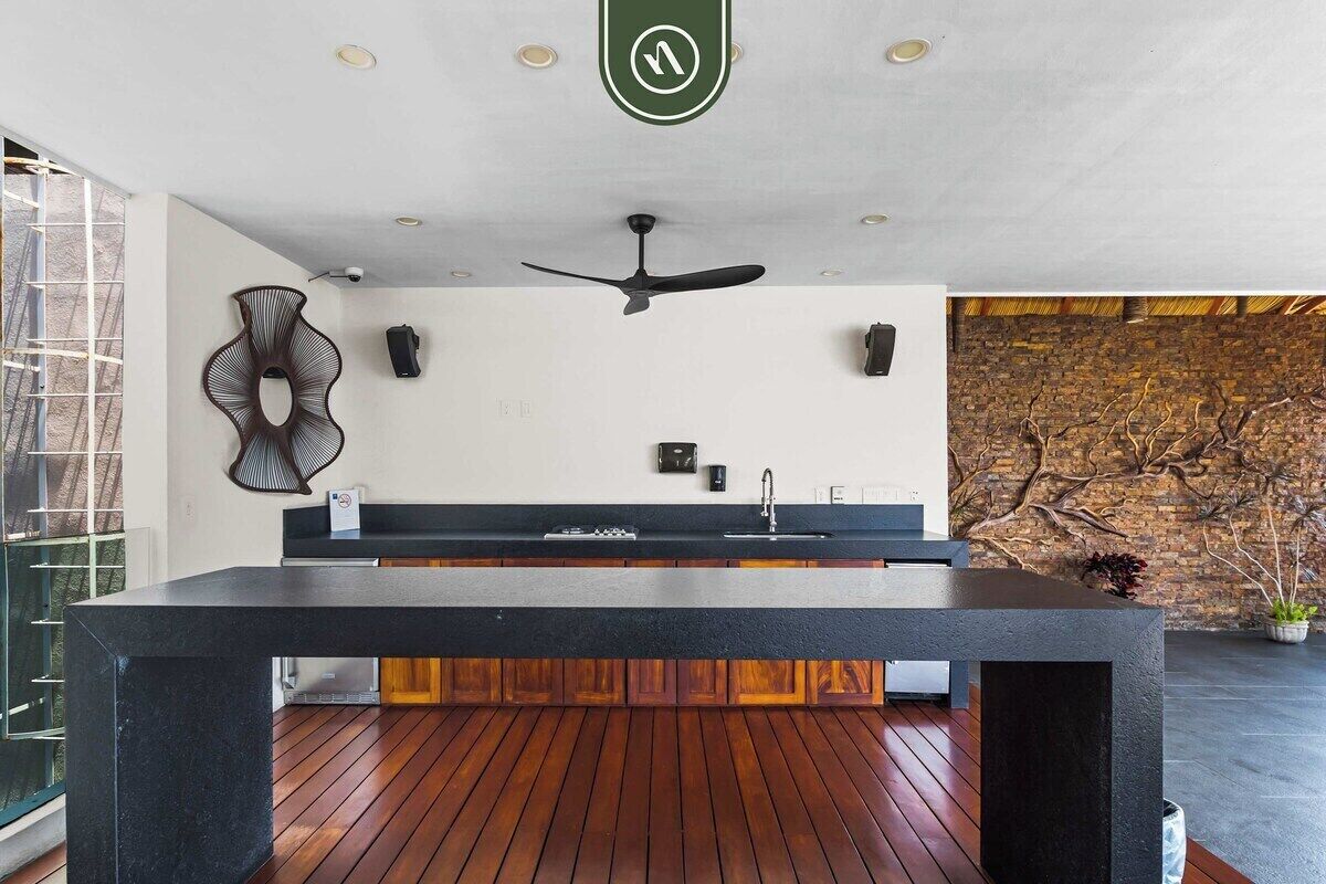 A modern kitchen with a central island, wooden flooring, and a ceiling fan.