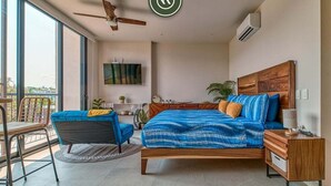 A bedroom with a large bed, a desk, a chair, and a balcony. - Brand New Studio - 2 Min to Beach - Rooftop Pool (Bucerías)
