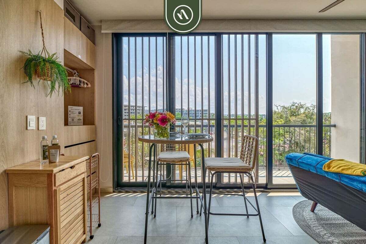 A balcony with a view, a dining table with chairs, a sofa, and a small kitchenette.