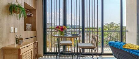 A balcony with a view, a dining table with chairs, a sofa, and a small kitchenette.
