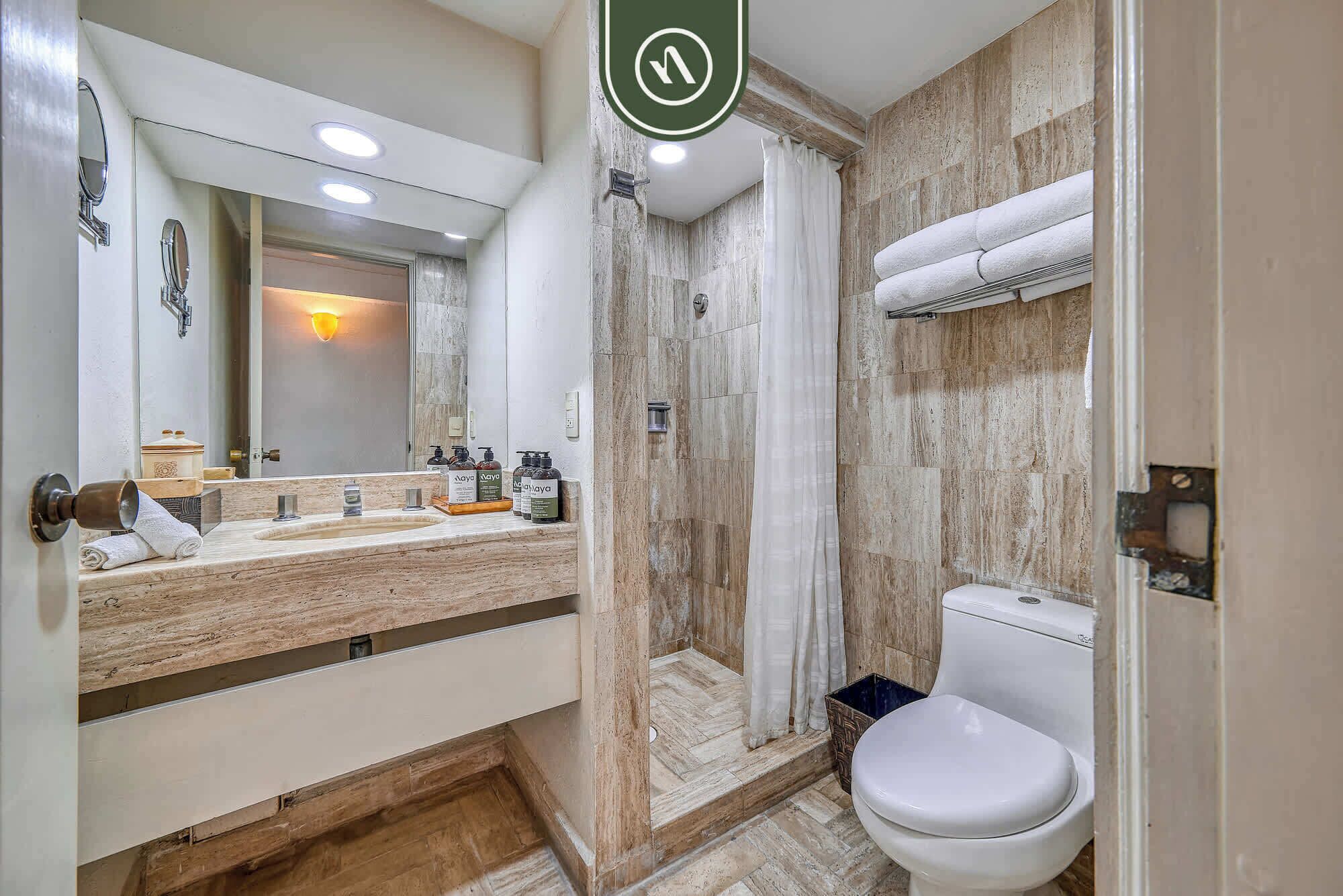 A bathroom with a shower, toilet, and vanity with a mirror.