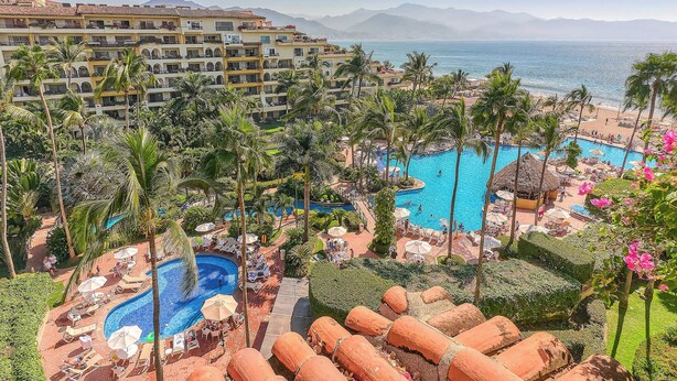 A resort with multiple swimming pools, palm trees, and a view of the sea. - Beachfront 2 BR Condo - Beach - Pools - Tennis (Puerto Vallarta)