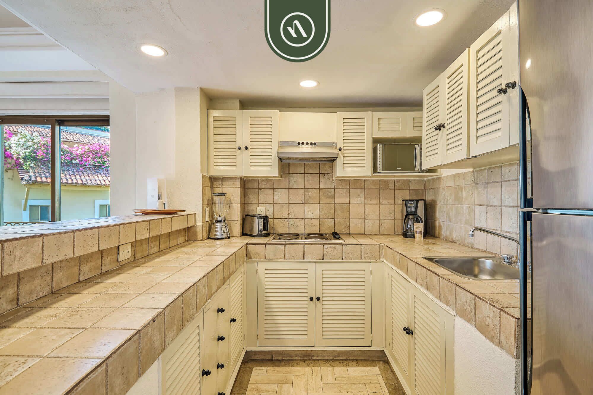 A kitchen with white cabinets, a stove, a sink, and a refrigerator.