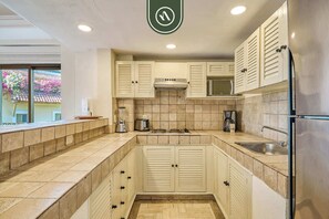 A kitchen with white cabinets, a stove, a sink, and a refrigerator. - Beachfront 2 BR Condo - Beach - Pools - Tennis (Puerto Vallarta)