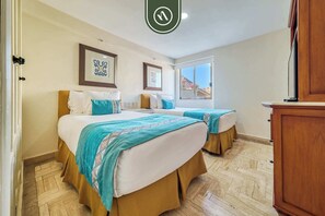 A hotel room with two beds, a wooden cabinet, and a window with a view. - Beachfront 2 BR Condo - Beach - Pools - Tennis (Puerto Vallarta)