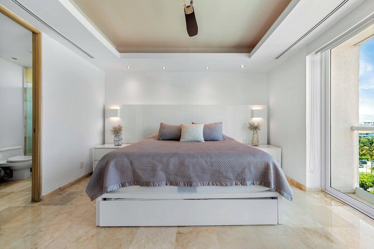 Une chambre à coucher moderne, avec un lit, des tables de chevet et une grande fenêtre.