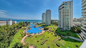 Un resort con piscina, exuberante vegetación y edificios altos.