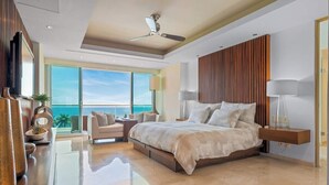 A modern bedroom with a large bed, a ceiling fan, a TV, and a view of the ocean. - Luxury Oceanfront 4BR Condo - Pool - Ocean View (Puerto Vallarta)